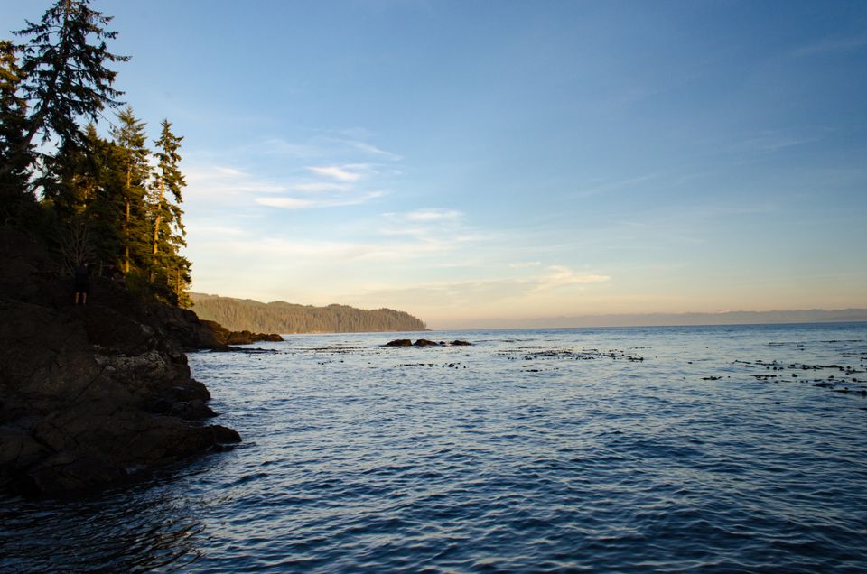 Landscape image of the ocean at sunset, with a small amount of foreshore illuminated by they setting sun